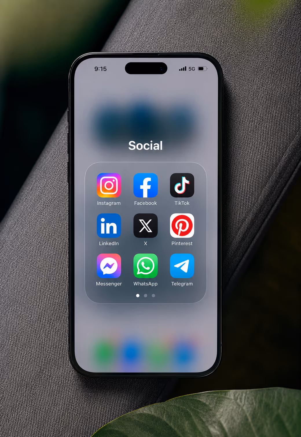 A smartphone on a couch showing the Social app folder